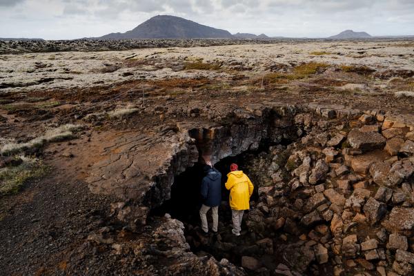 Dos personas entrando a la cueva de lava Leiðarendi