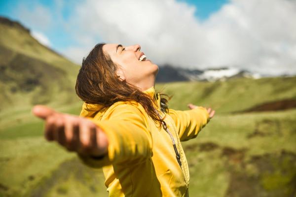 Nature of Iceland happy woman looking at the sky, in the middle of the green landscape of Iceland