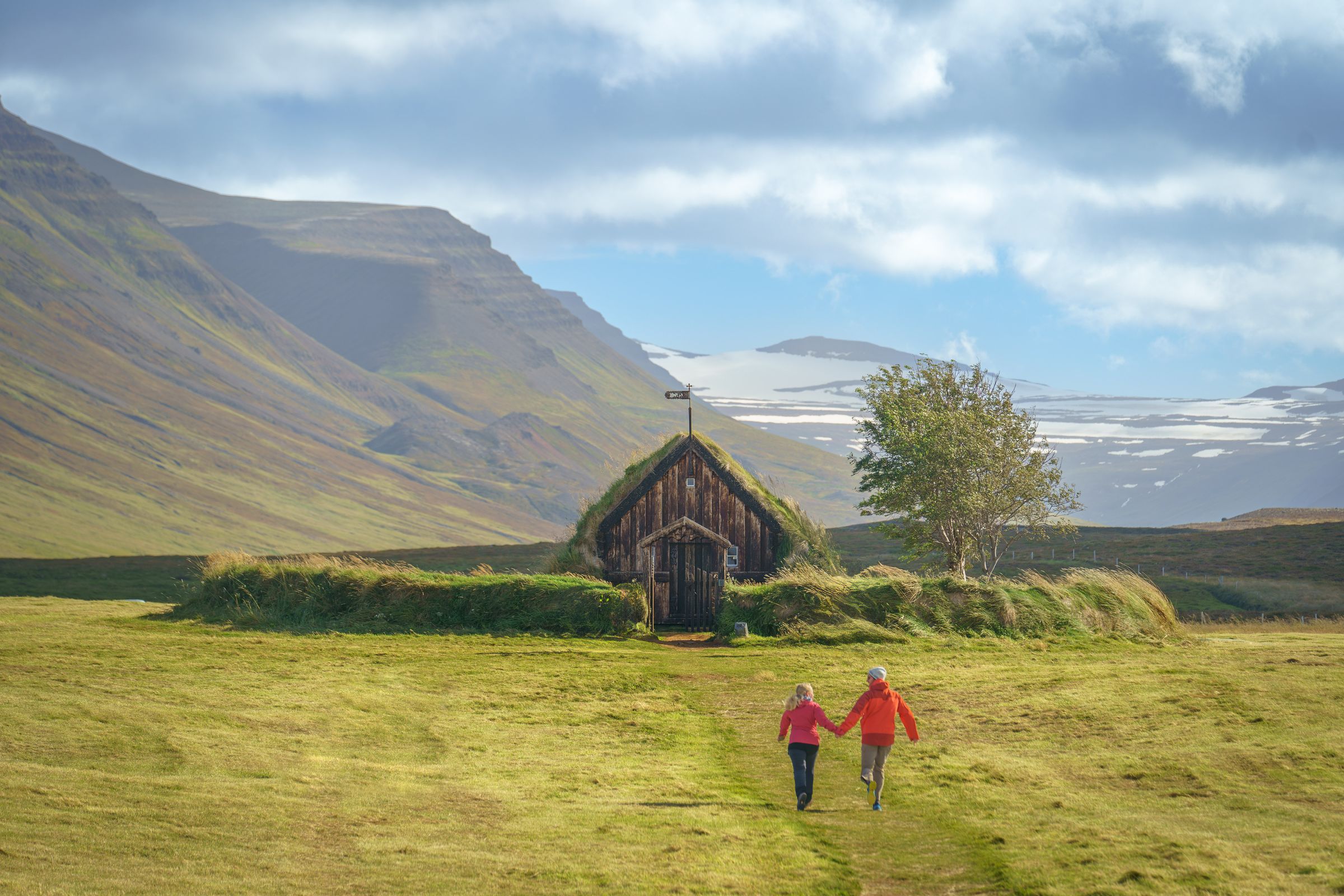 a couple of people are walking in a field in front of a church .