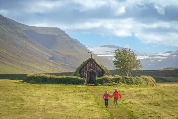 a couple of people are walking in a field in front of a church .