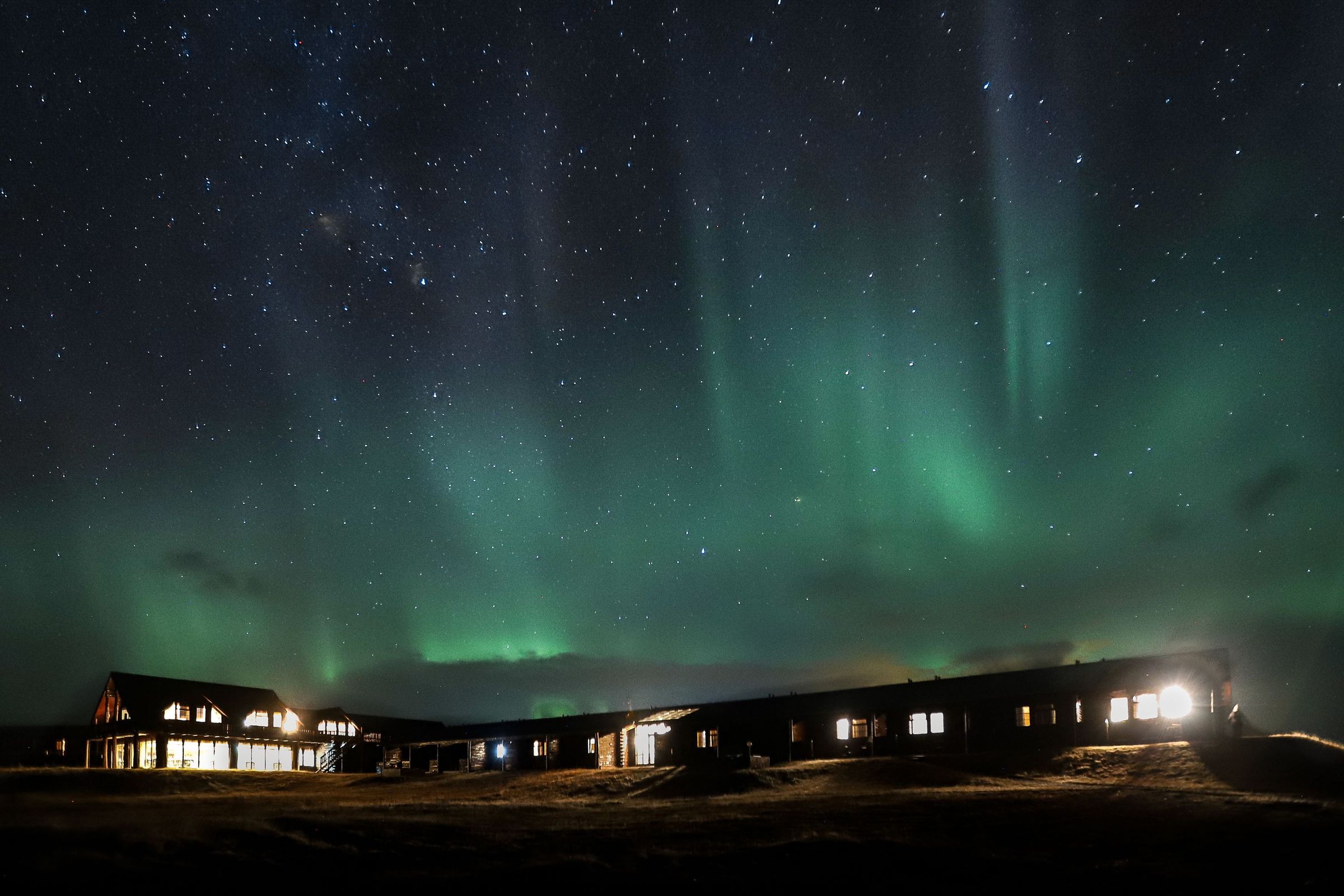 the aurora borealis is shining over a hotel at night .