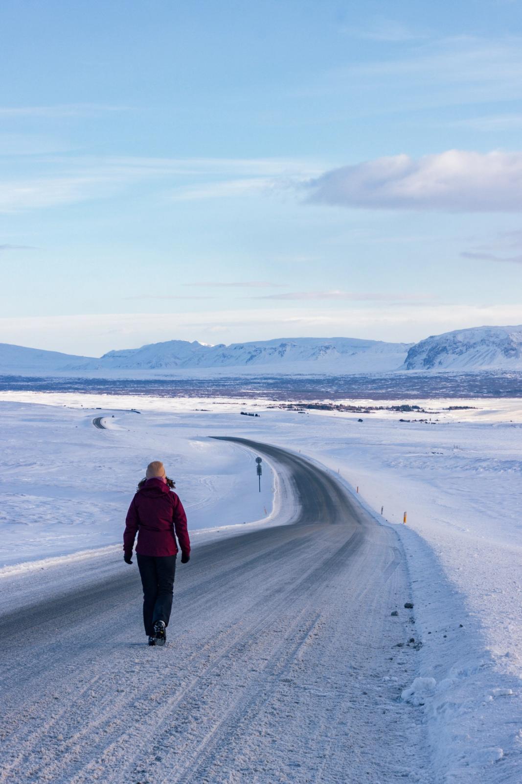 Femme marchant sur une route entièrement couverte de neige