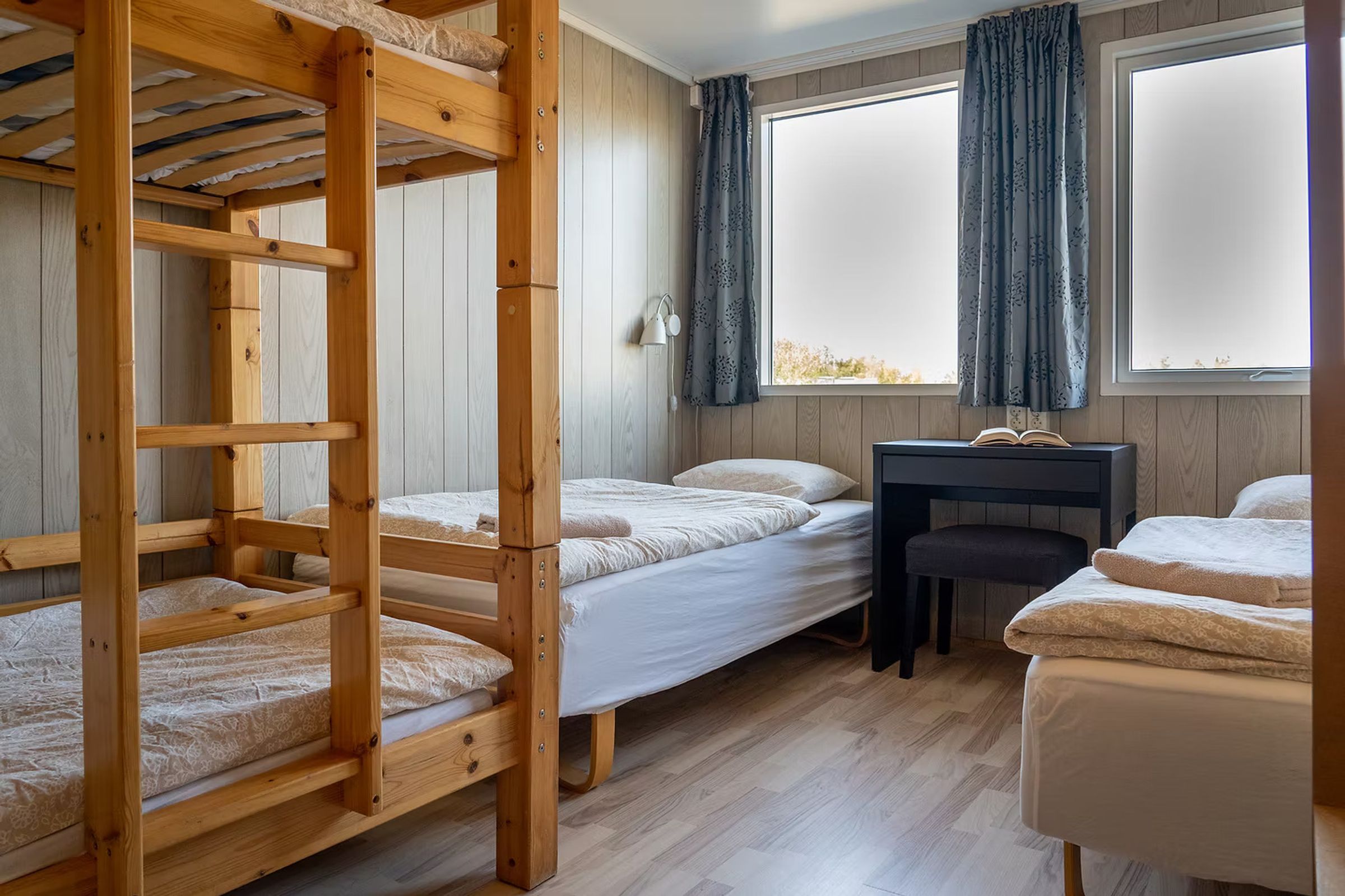 un dormitorio con literas, un escritorio y una ventana.