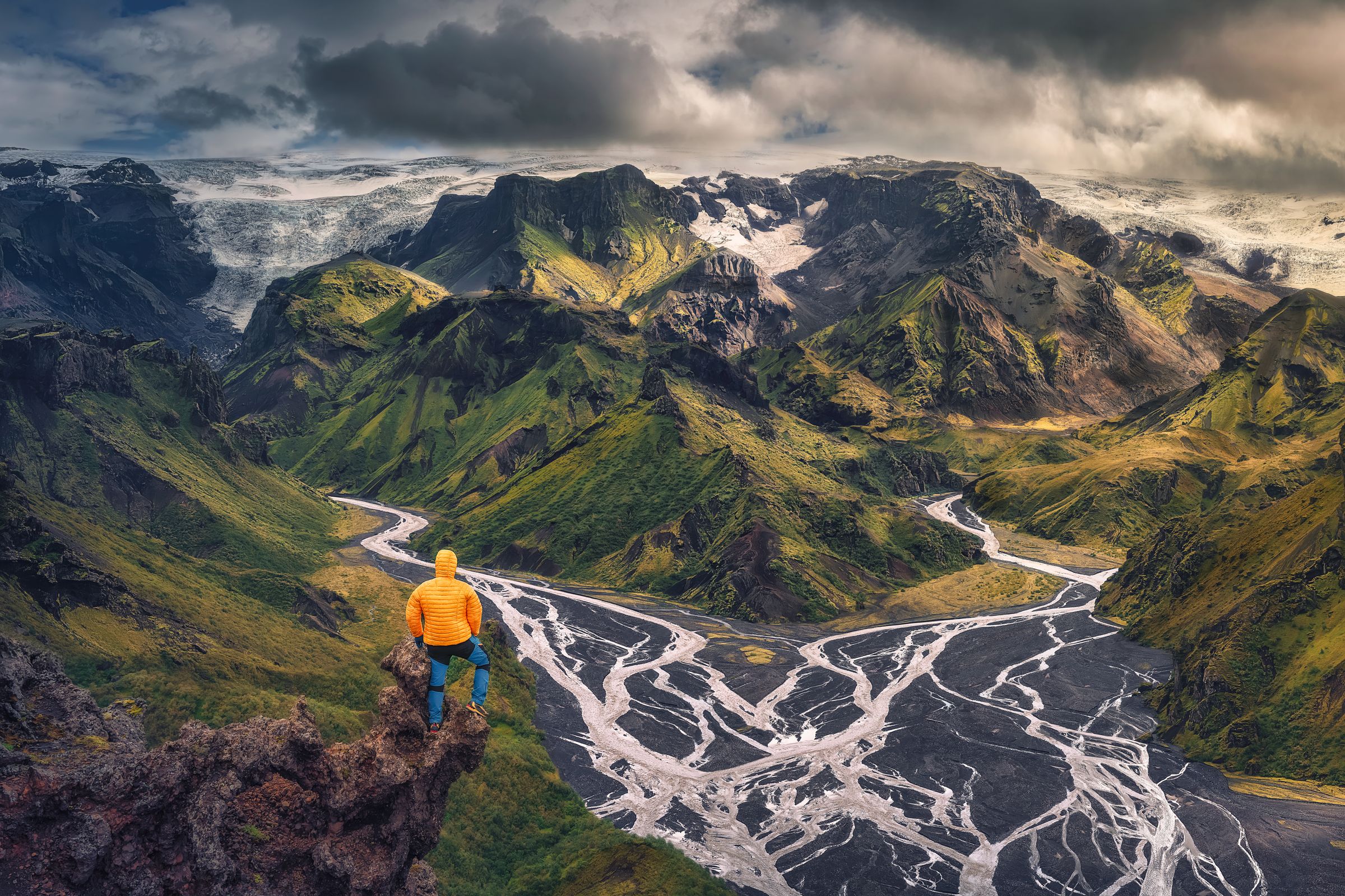 Un homme se tient au sommet d'une montagne surplombant une rivière à Þórsmörk en Islande.