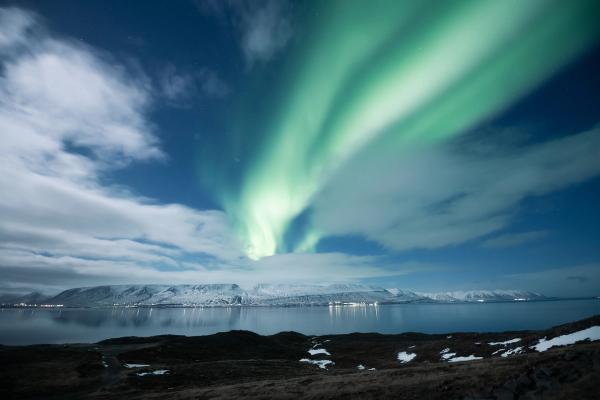the northern lights are dancing in the sky over a lake at Akureyri in north iceland.