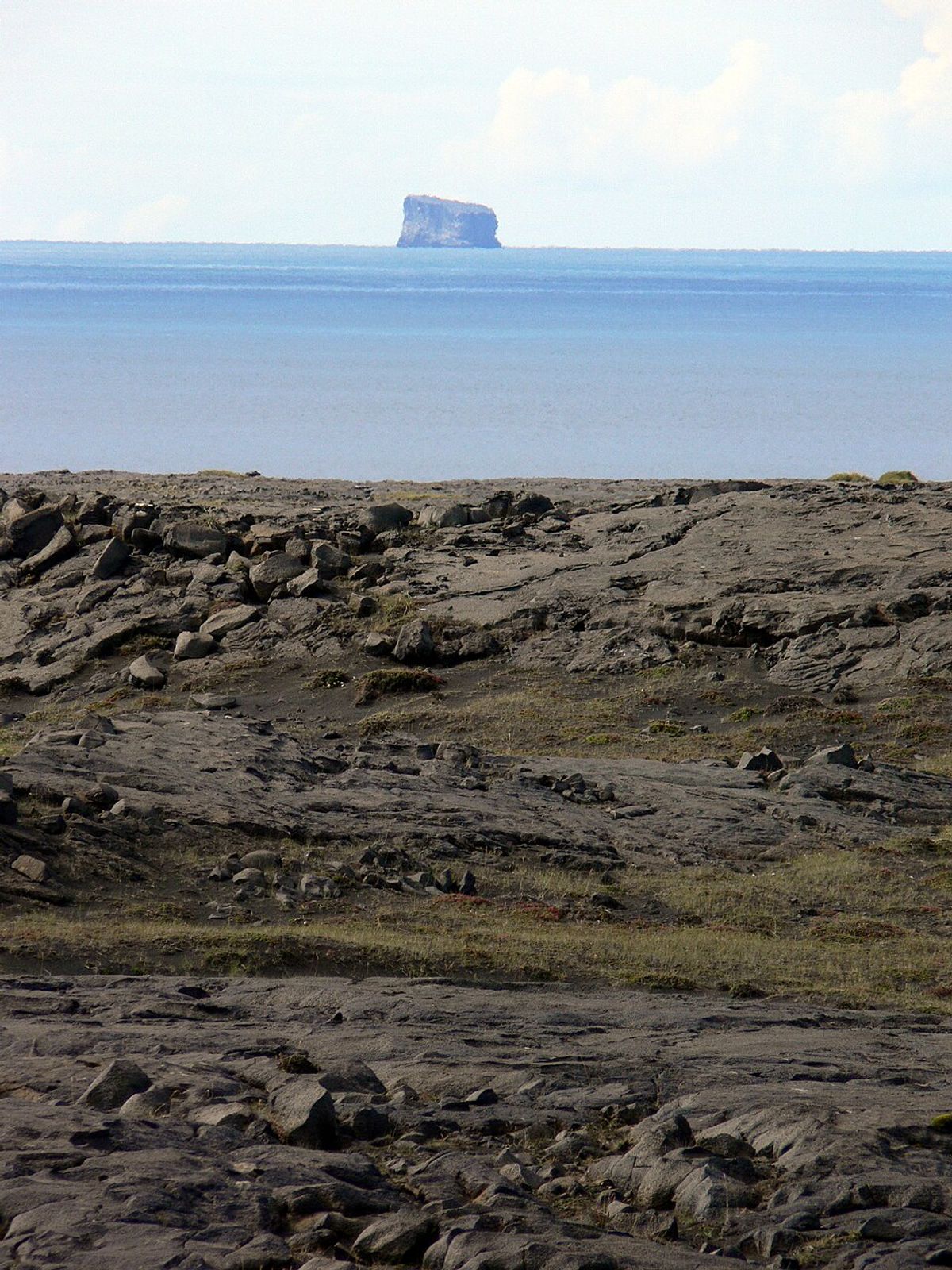 a rocky shoreline with a large island in the distance