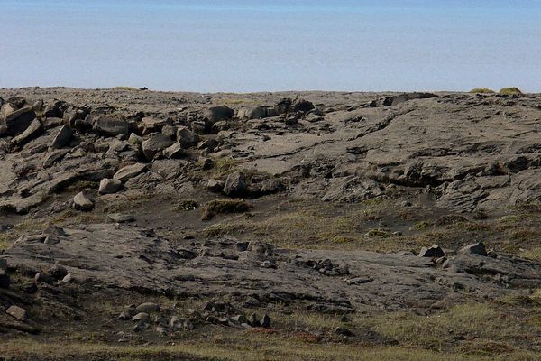 a rocky shoreline with a large island in the distance