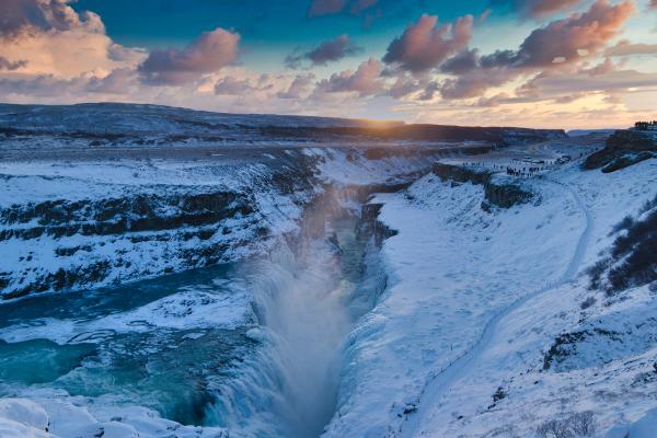 a waterfall in the middle of a snowy canyon at sunset at gullfoss in Iceland,