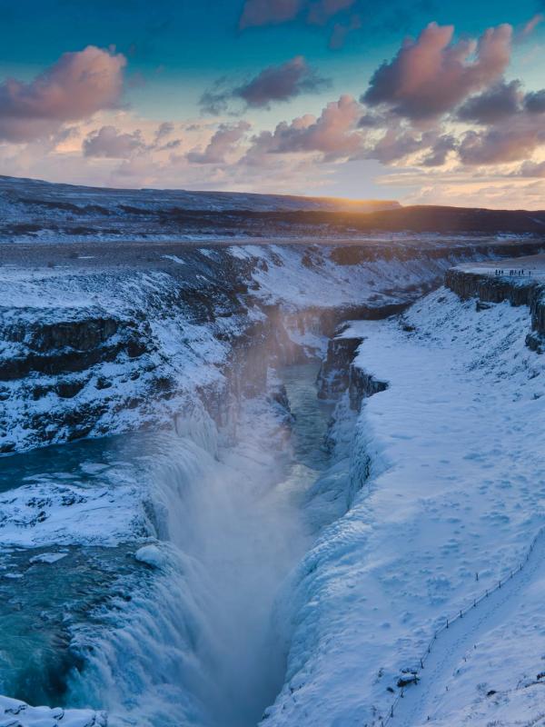 a waterfall in the middle of a snowy canyon at sunset at gullfoss in Iceland,