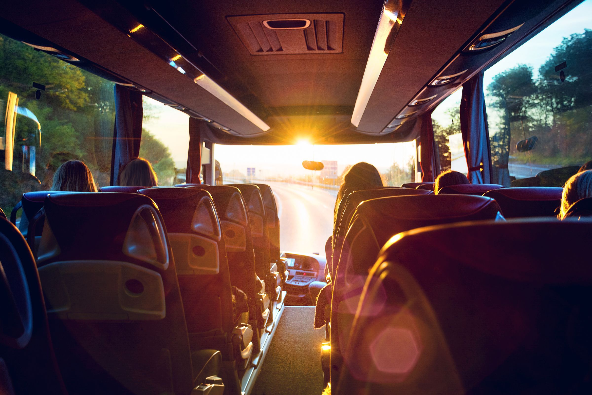 el sol brilla a través de las ventanas de un autobús lleno de gente.