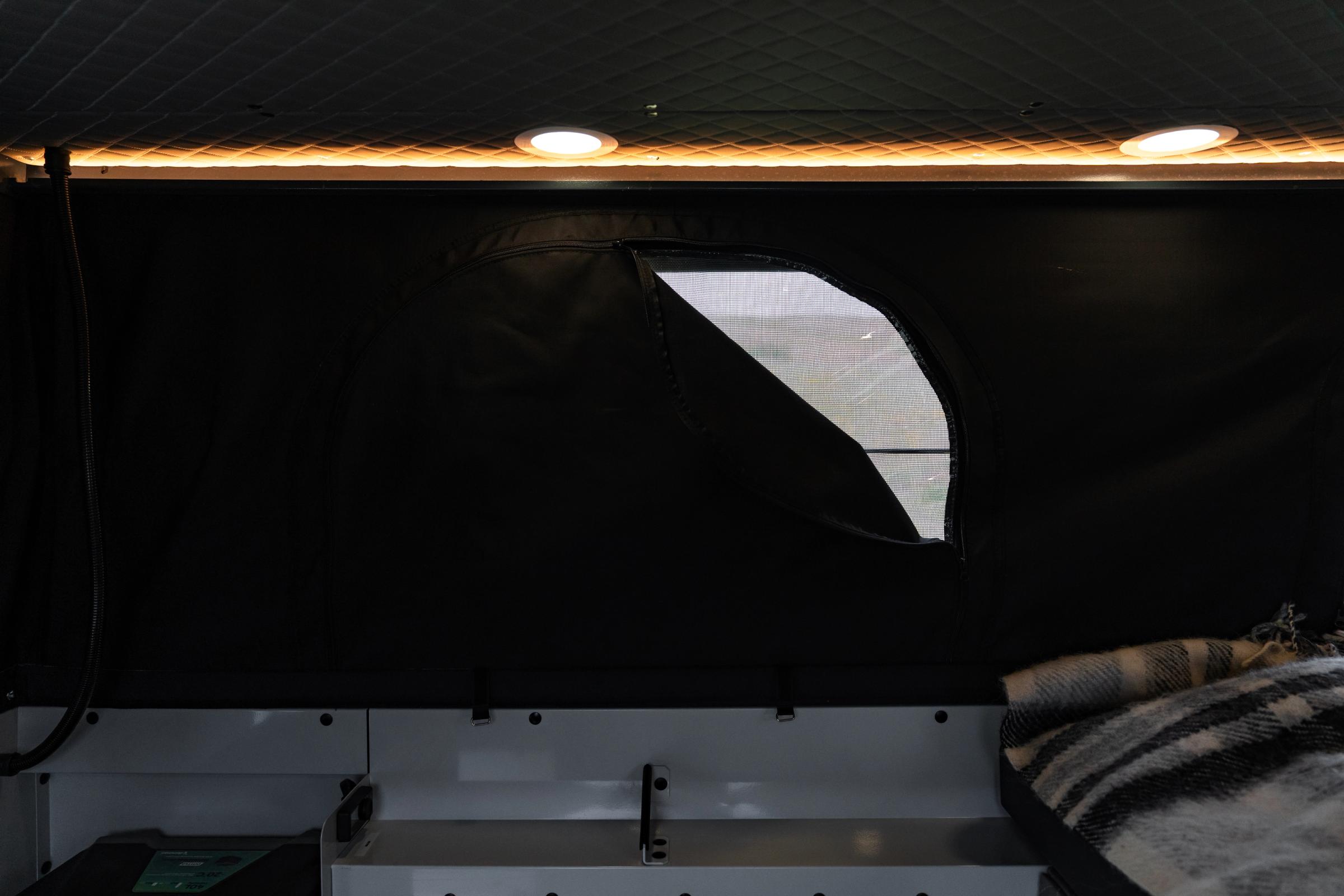Ventana de malla con cremallera en la pared del techo elevable, debajo de los focos LED y la tira de iluminación