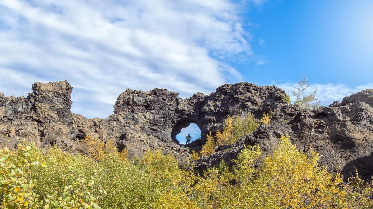 a person is standing in a hole in a rock formation at dimmuborgir in Myvatn are in iceland.