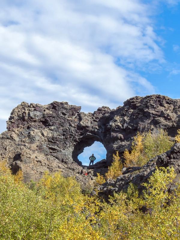 a person is standing in a hole in a rock formation at dimmuborgir in Myvatn are in iceland.