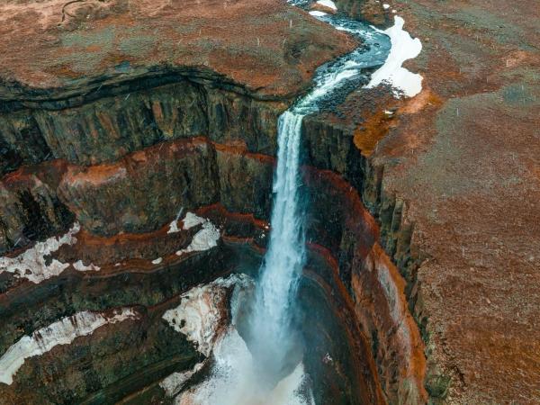 an aerial view of a waterfall in the middle of a canyon .