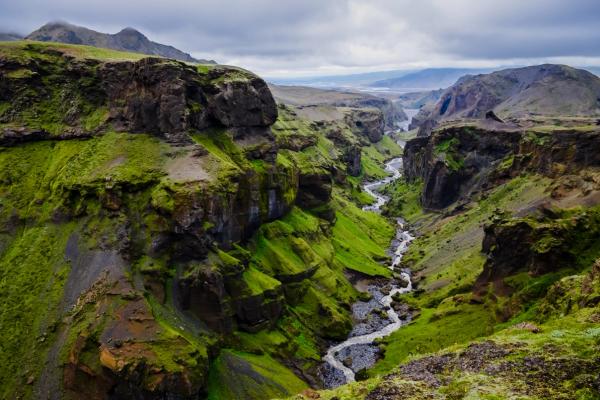 a river flowing through a lush green canyon surrounded by mountains at Þórsmörk in Iceland.