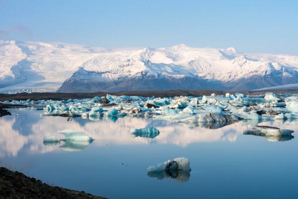 a lake filled with icebergs and mountains in the background .
