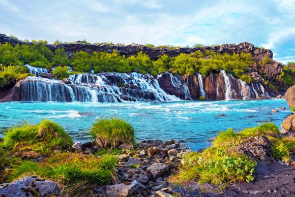 a waterfall in the middle of a river surrounded by rocks and grass .