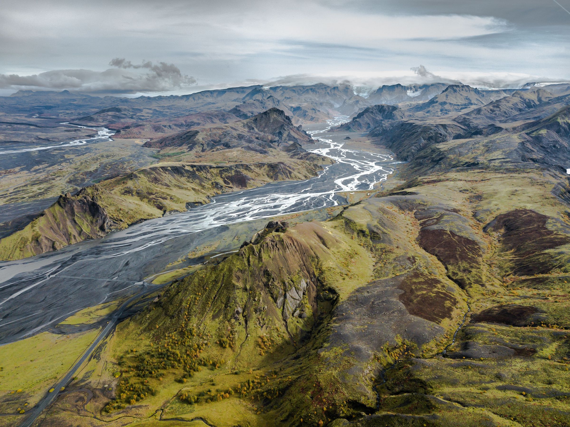 an aerial view of a river running through a valley surrounded by mountains .