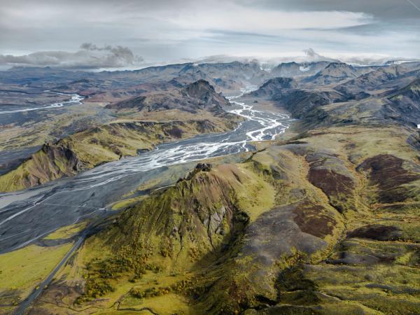an aerial view of a river running through a valley surrounded by mountains .
