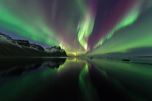 the aurora borealis is reflected in the water of a lake in iceland .