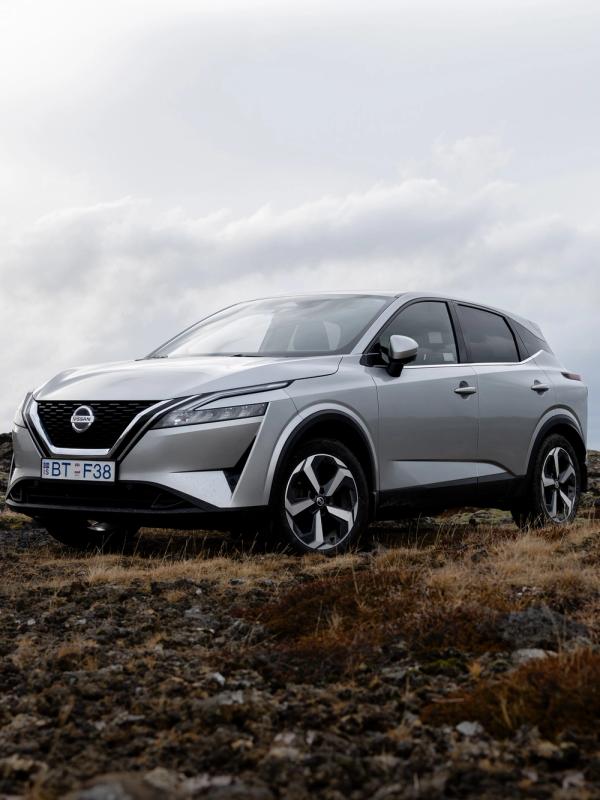 A silver Nissan Qashqai SUV parked on a rocky landscape under a cloudy sky.