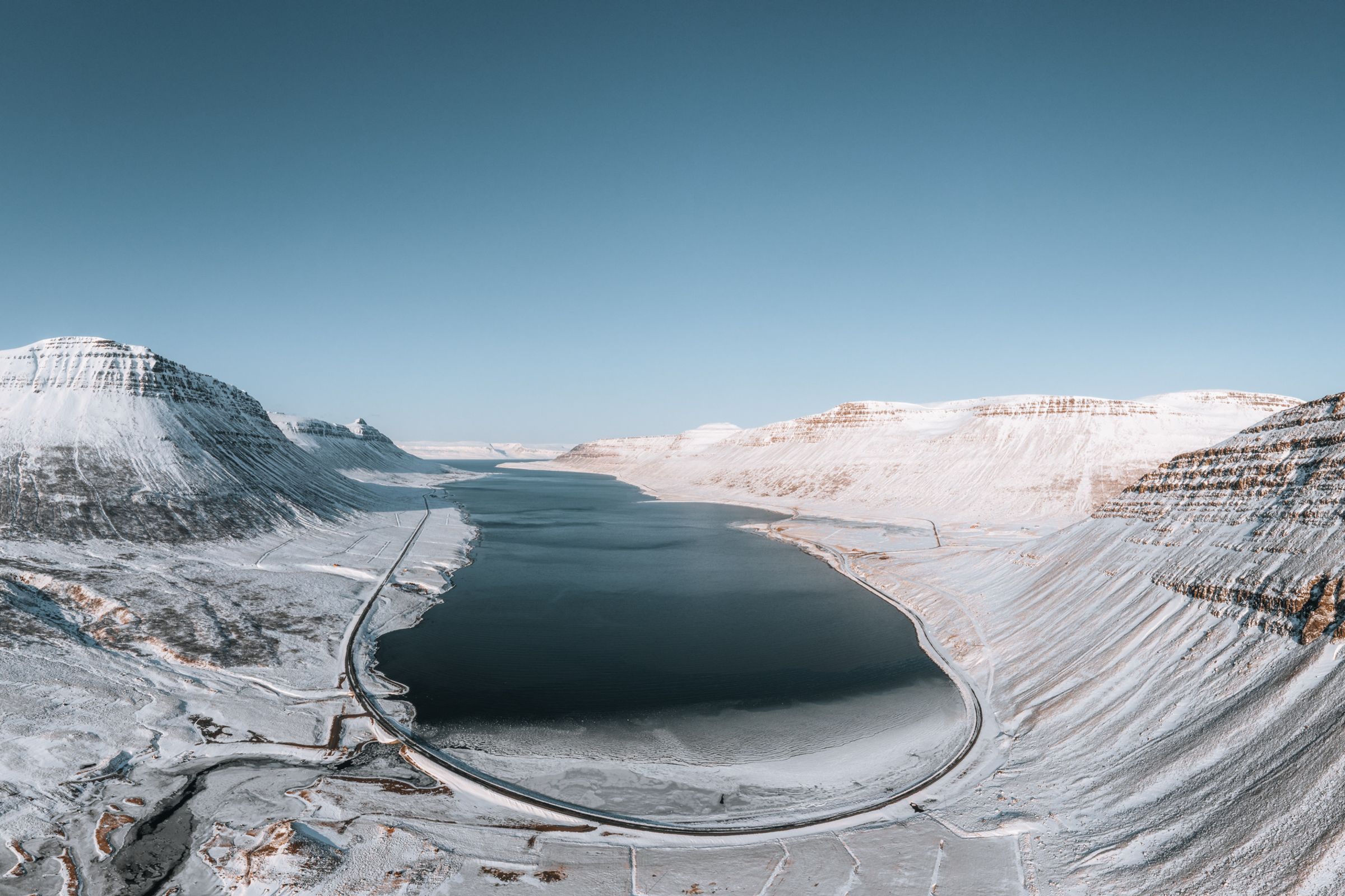 an aerial view of a snowy mountain range with a lake in the middle .