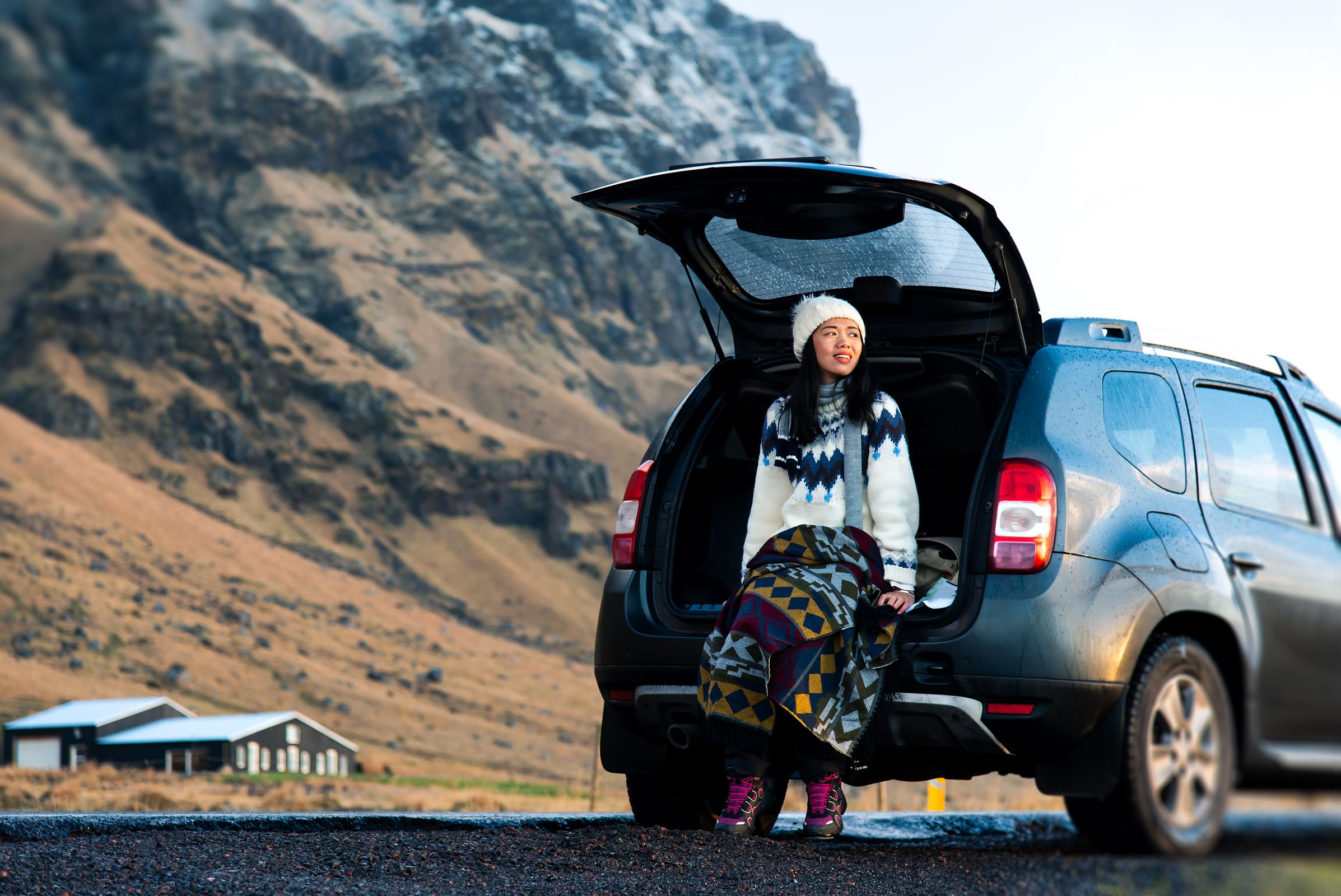 a woman is sitting in the back of a car wearing a hat in iceland,