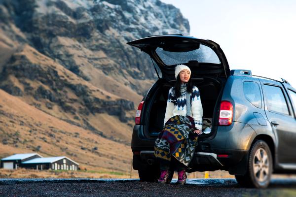 a woman is sitting in the back of a car wearing a hat in iceland,