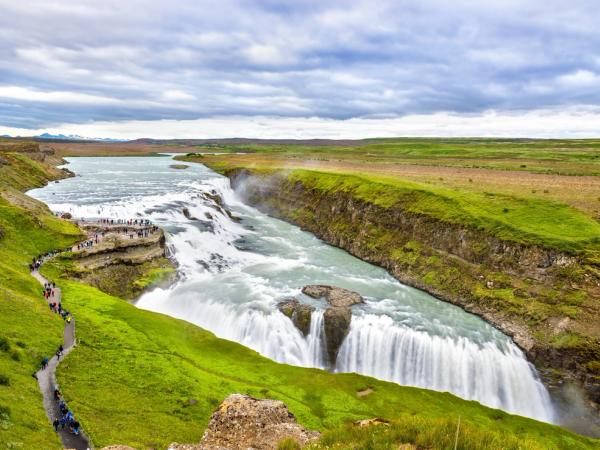 a waterfall in the middle of a river surrounded by grass and rocks .