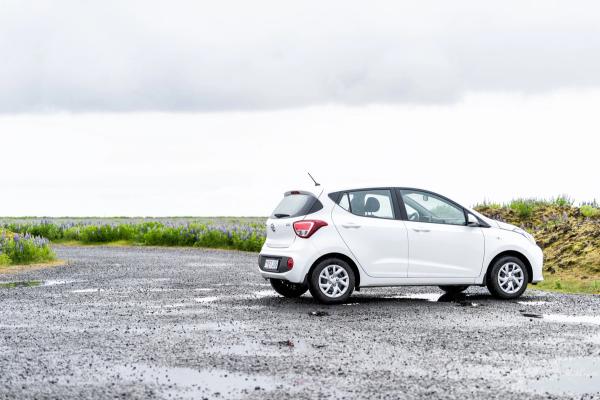Explore the mesmerizing landscapes of Iceland in our reliable Hyundai i10 rental car. White Hyundai i10 rental car parked on a scenic Iceland route.