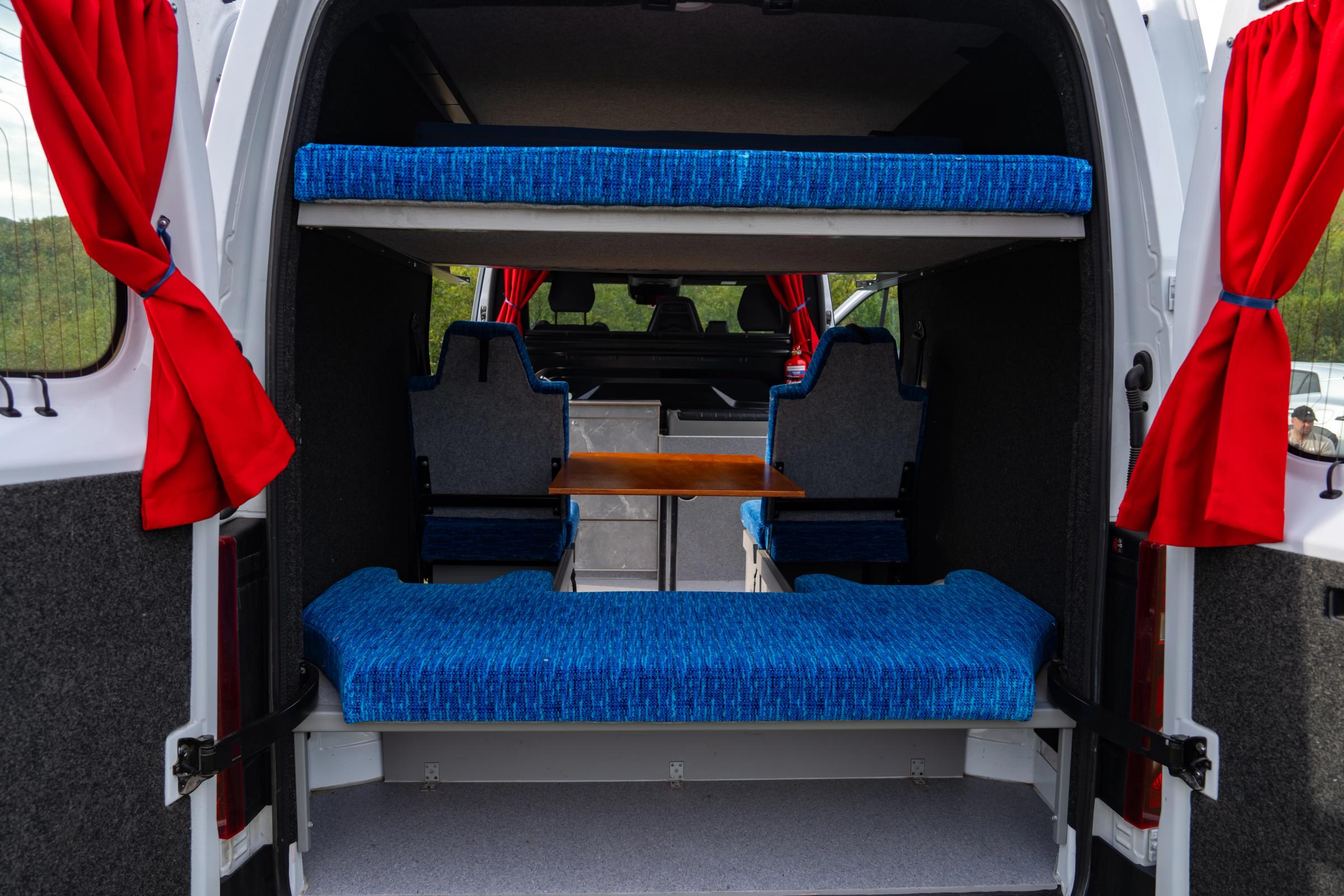 Upper bed and rear bench through the open back doors of a 5 person large camper