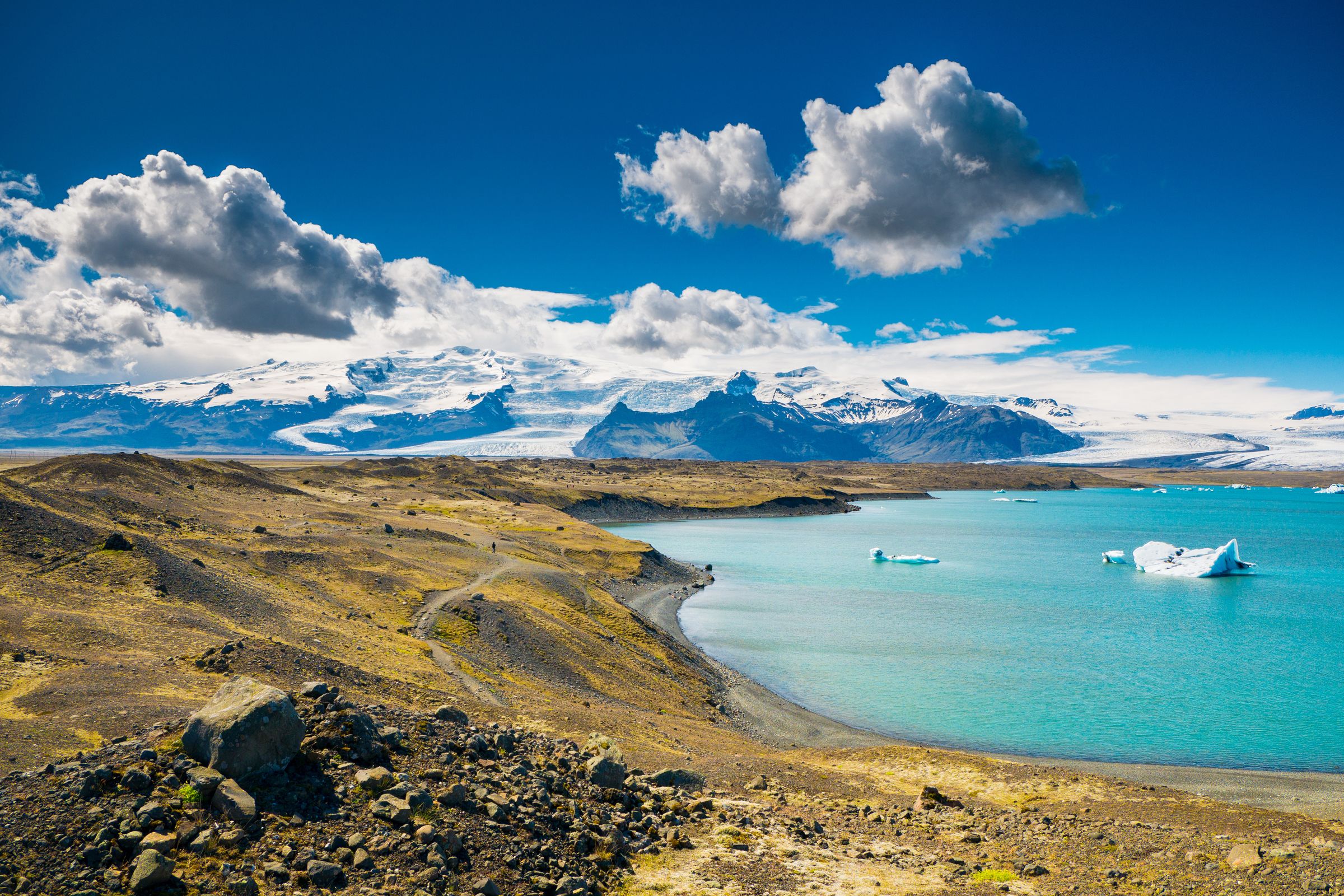Jökulsárlón with icebergs in it and mountains in the background .