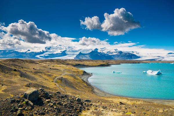 Jökulsárlón with icebergs in it and mountains in the background .