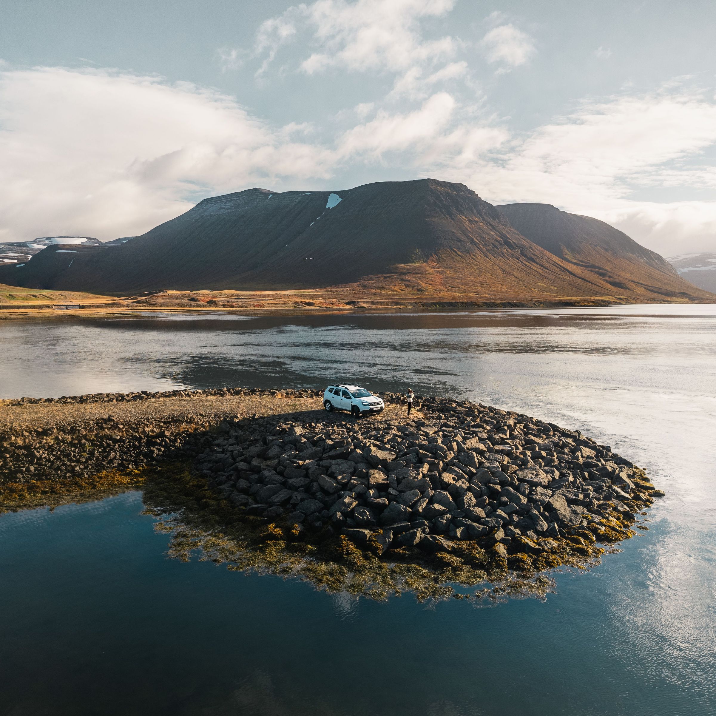 Coche blanco en el borde de un lago en Islandia