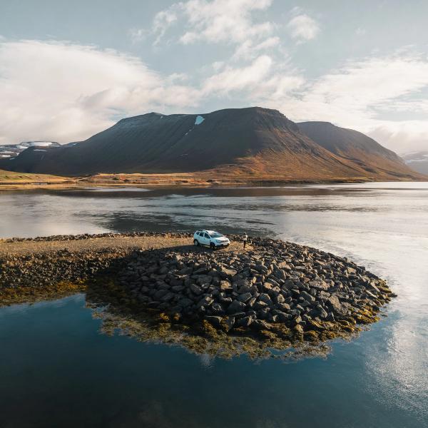 Coche blanco en el borde de un lago en Islandia