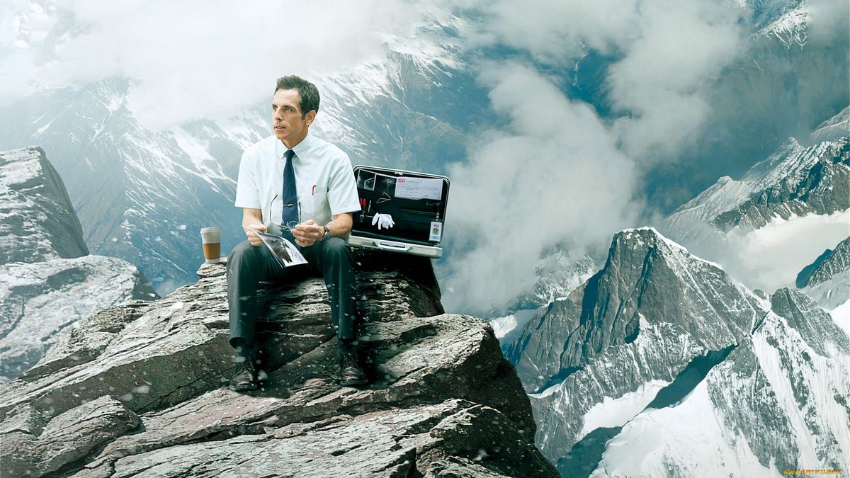 a man is sitting on top of a mountain with a briefcase .