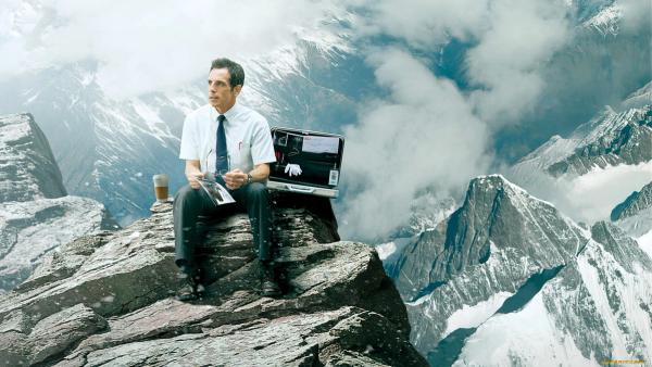 a man is sitting on top of a mountain with a briefcase .
