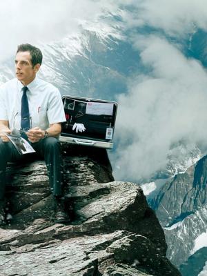 a man is sitting on top of a mountain with a briefcase .