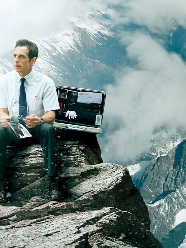 a man is sitting on top of a mountain with a briefcase .