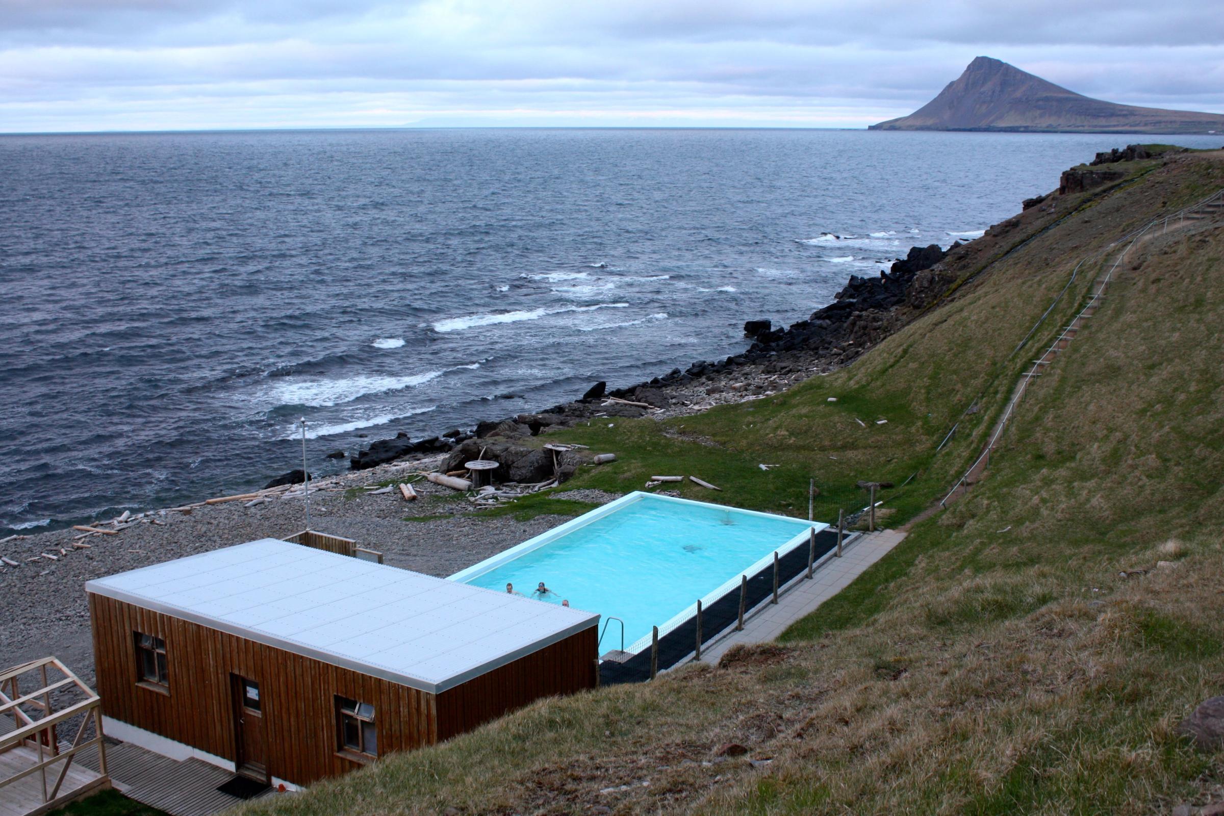 a large swimming pool is sitting on top of a hill next to the ocean .
