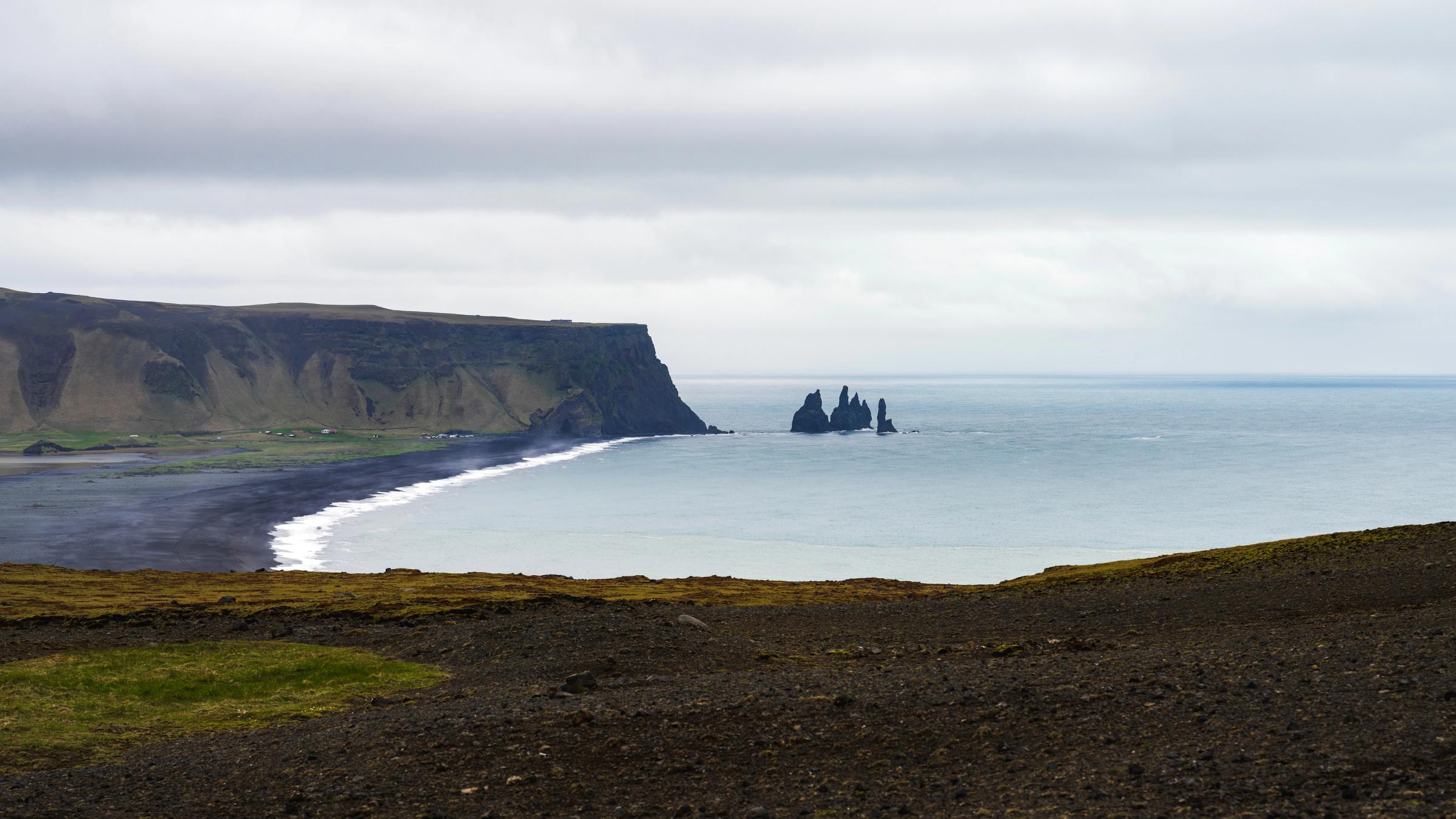 panoramic view of a black sand beach on a cloudy day