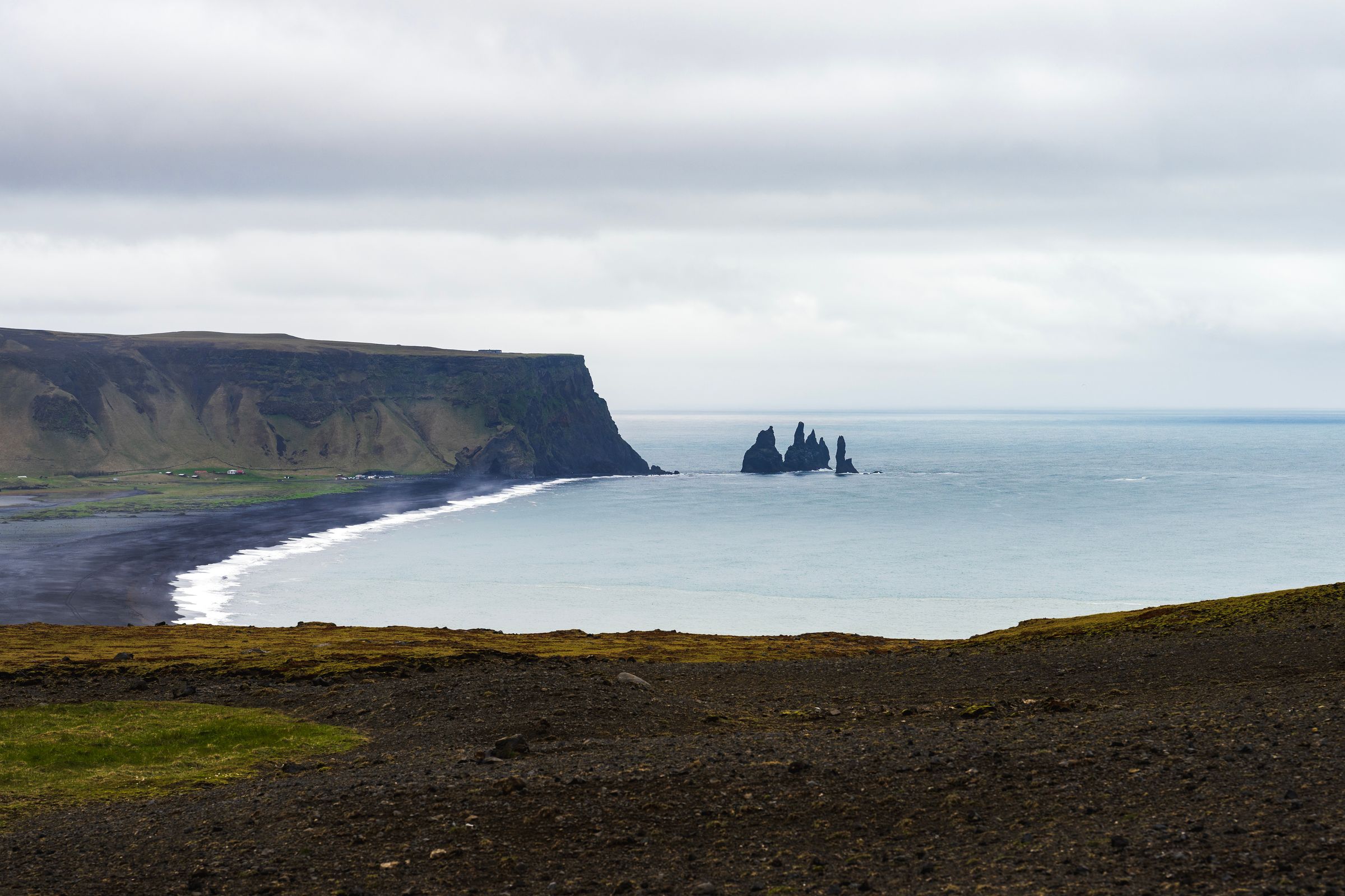 panoramic view of a black sand beach on a cloudy day