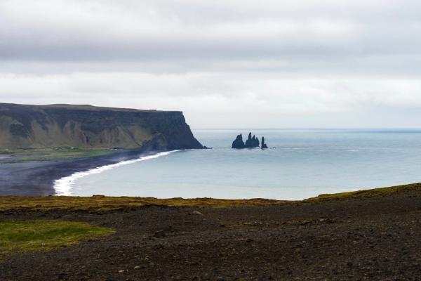 panoramic view of a black sand beach on a cloudy day