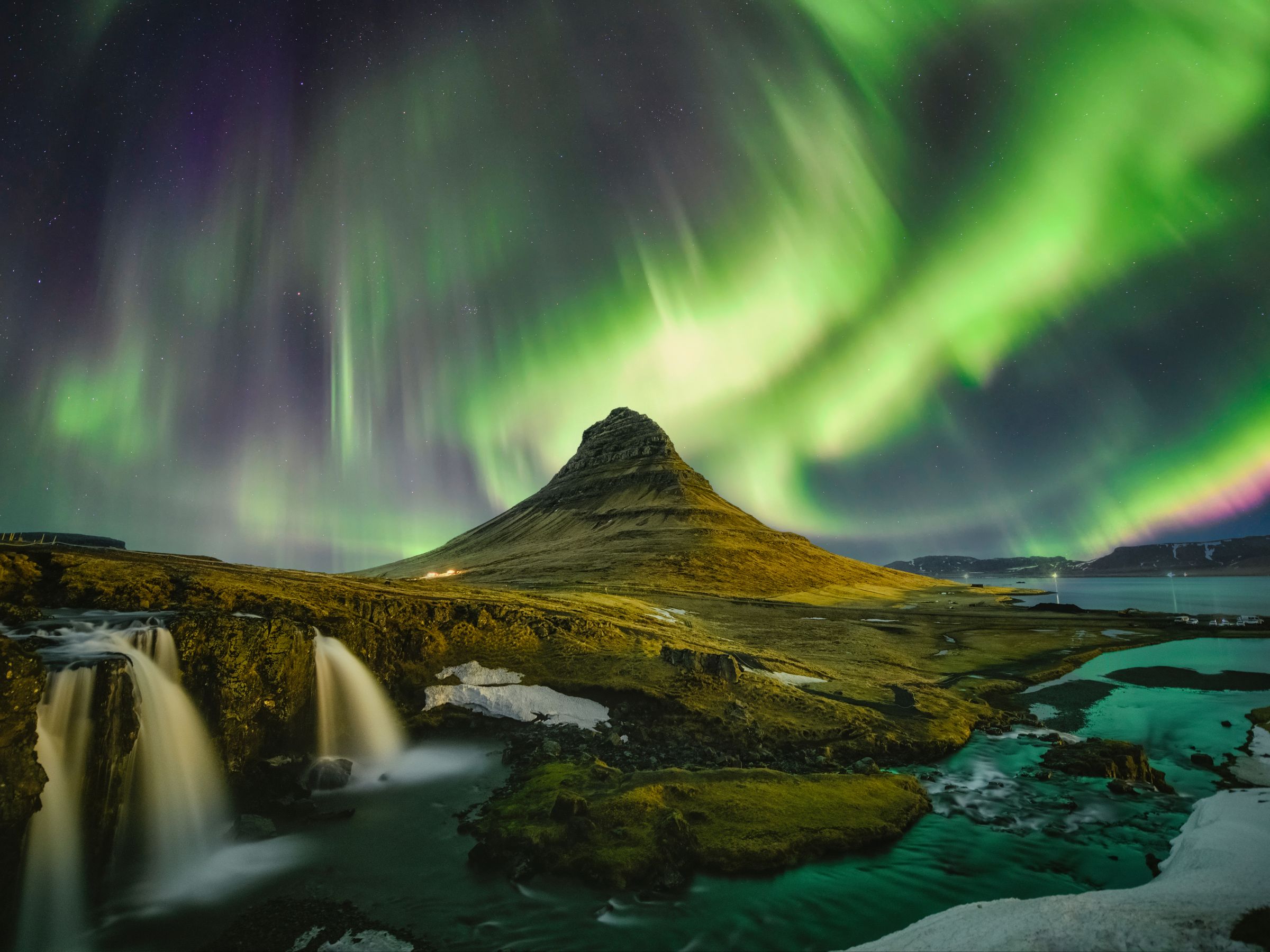 l'aurore boréale brille au-dessus d'une cascade et d'une montagne à Kirkufell, dans la péninsule de Snæfellsnes en Islande.