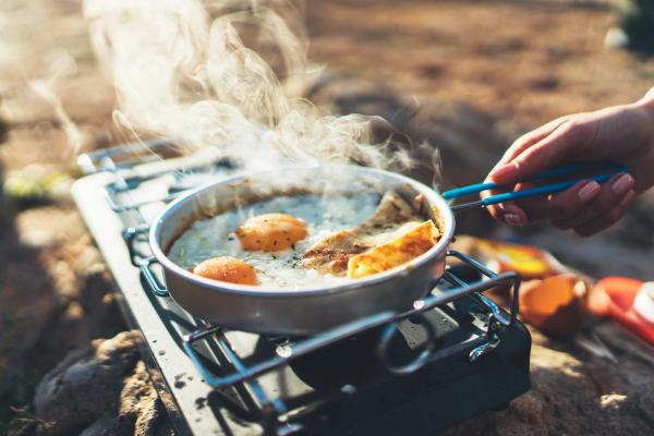 a person is cooking food on a gas stove in iceland.