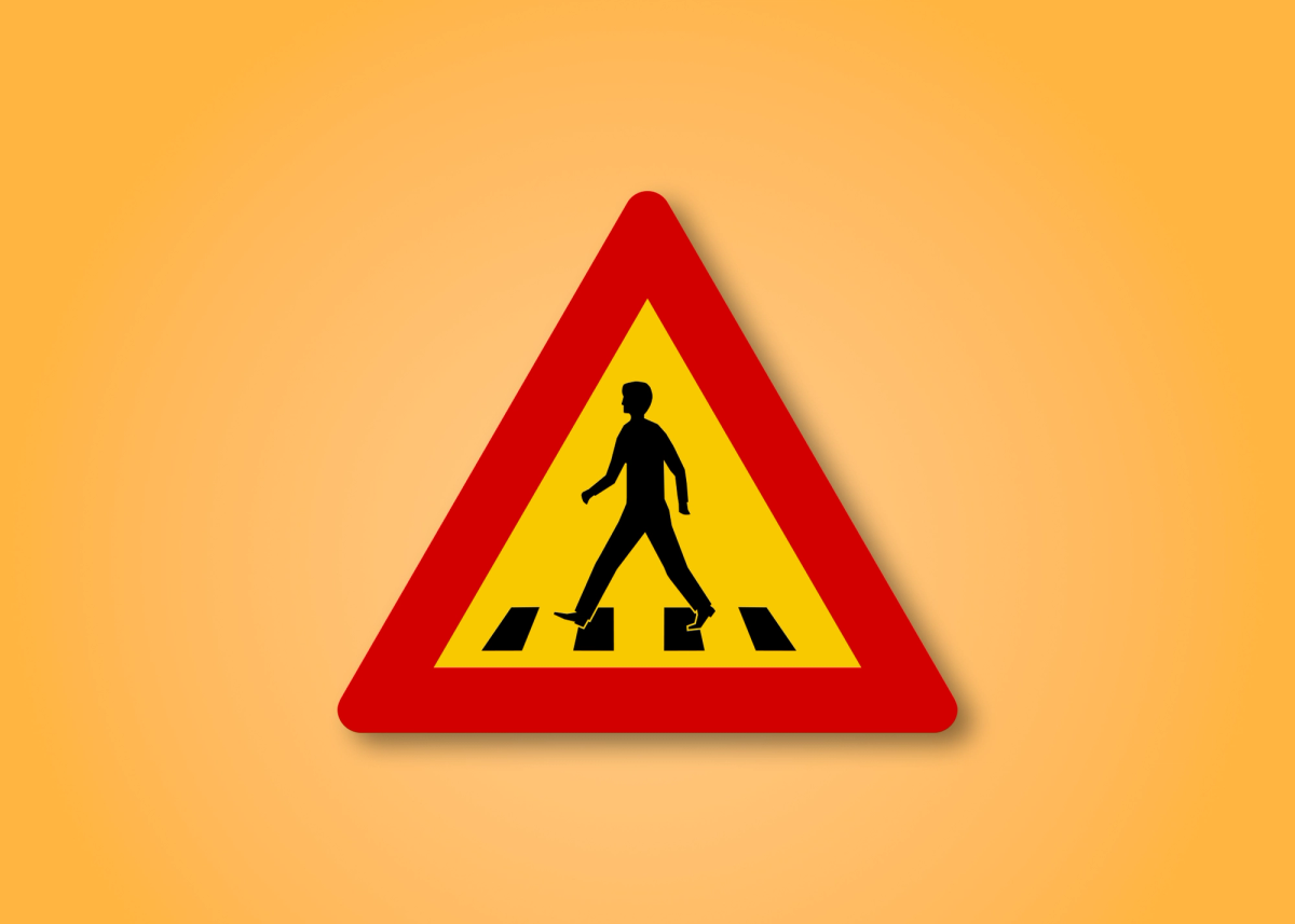a yellow and red sign shows a man crossing a crosswalk
