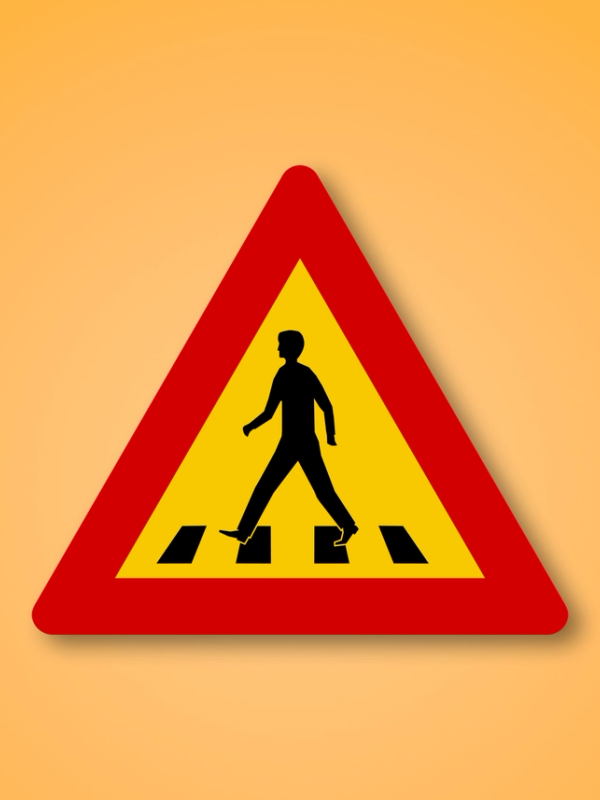 a yellow and red sign shows a man crossing a crosswalk