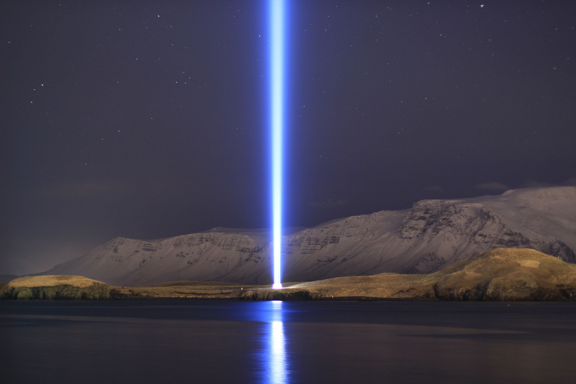 a light beam is shining over a lake at night .