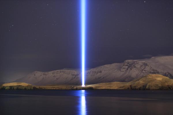 a light beam is shining over a lake at night .