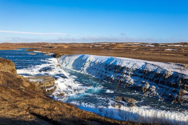 an aerial view of a waterfall in iceland on a sunny day .